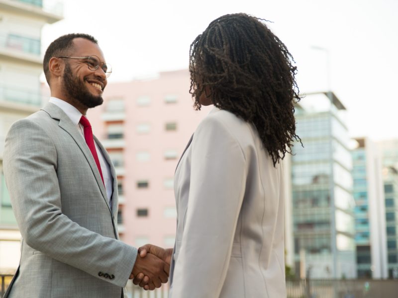 Business colleagues greeting each other near office